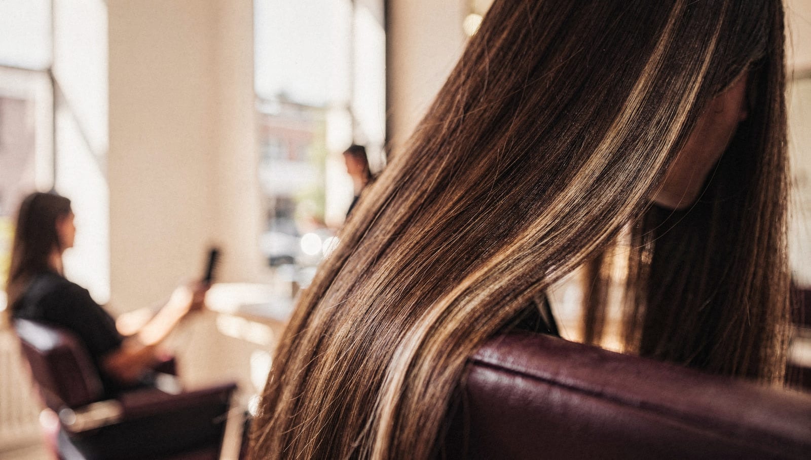 A sweep of glossy, freshly-highlighted hair catching warm window light