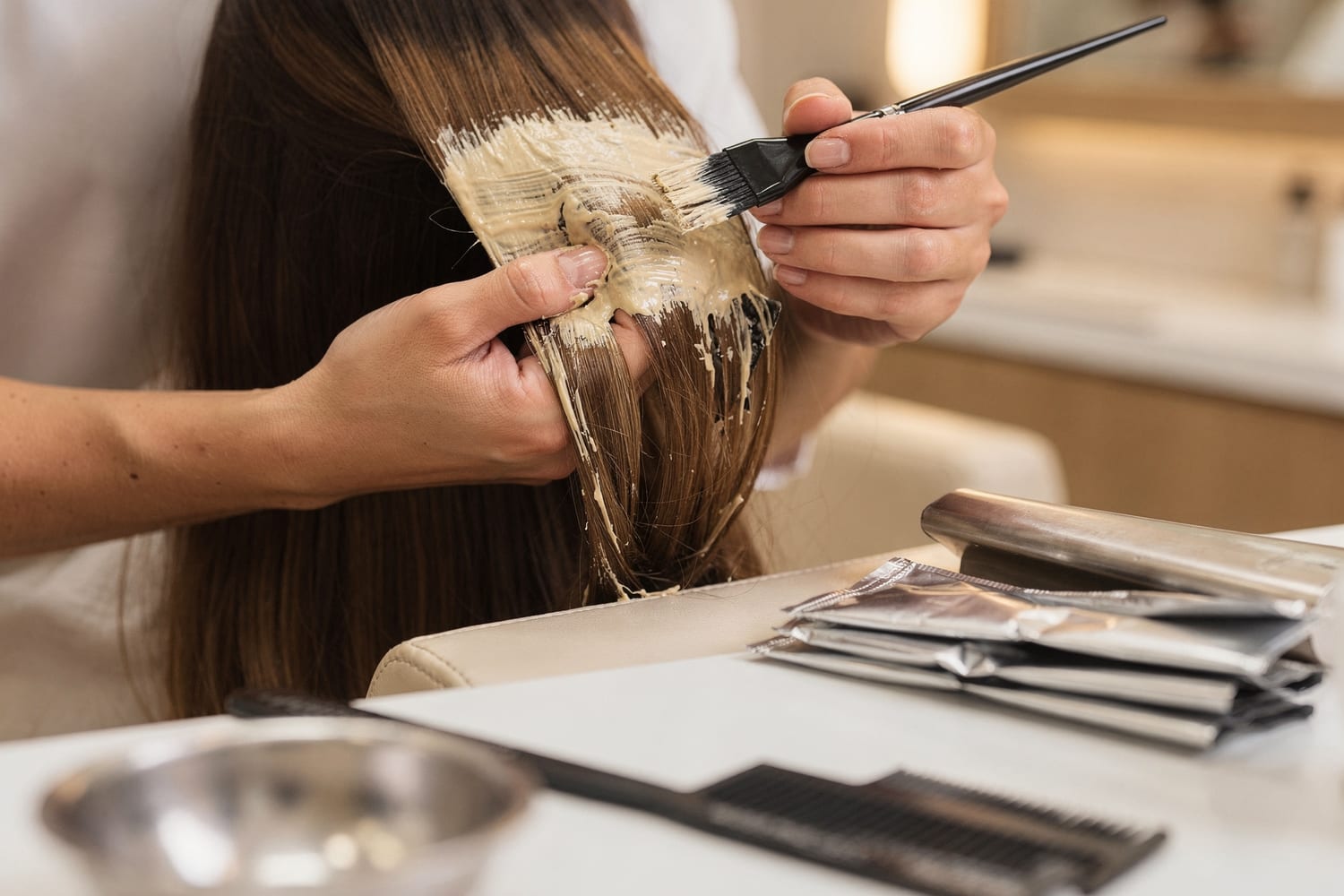 A stylist hand-painting balayage highlights onto a section of healthy hair